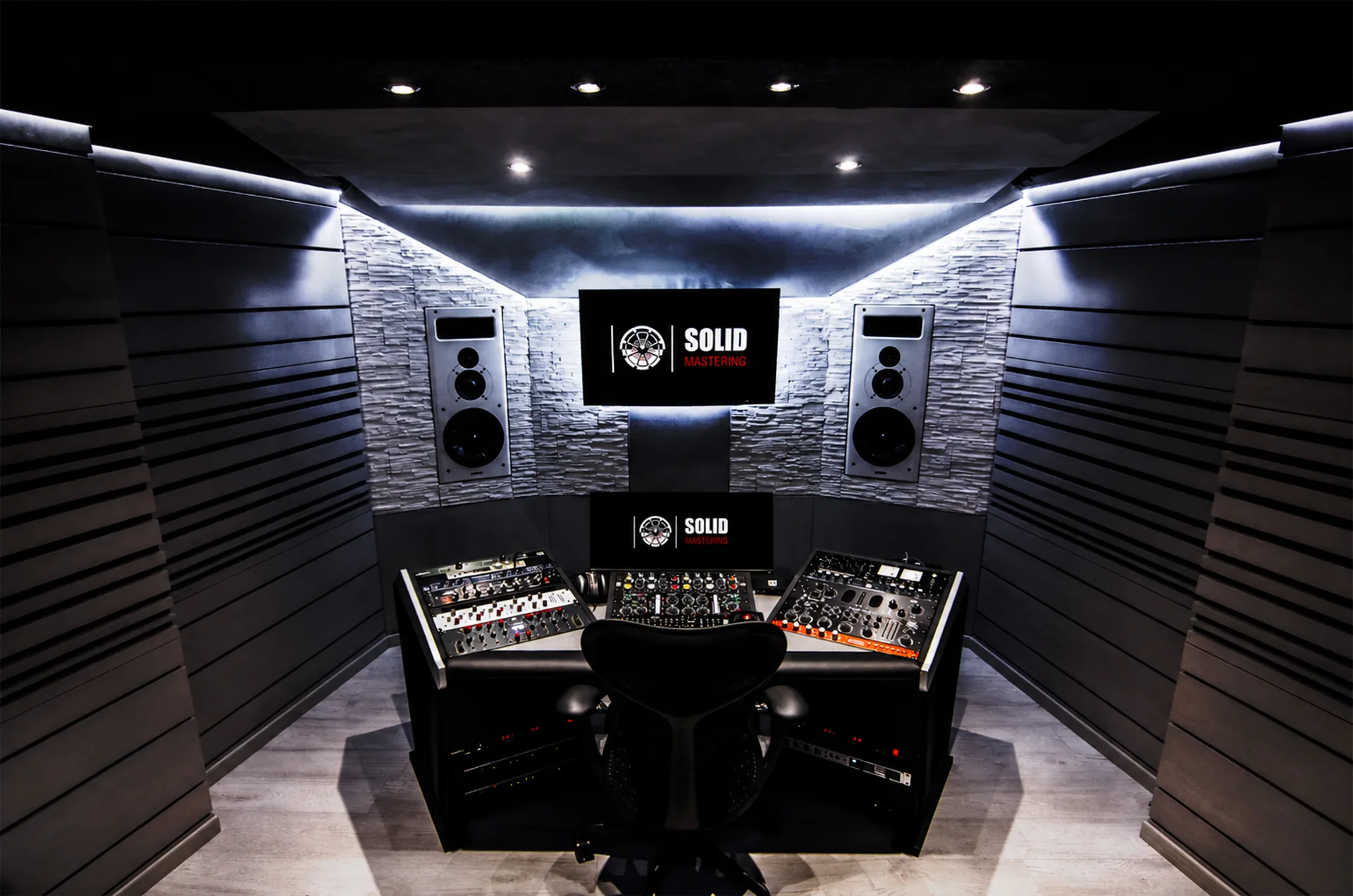 La sala de control de Solid Mastering de noche, con el logo de Solid Mastering en ambas pantallas.